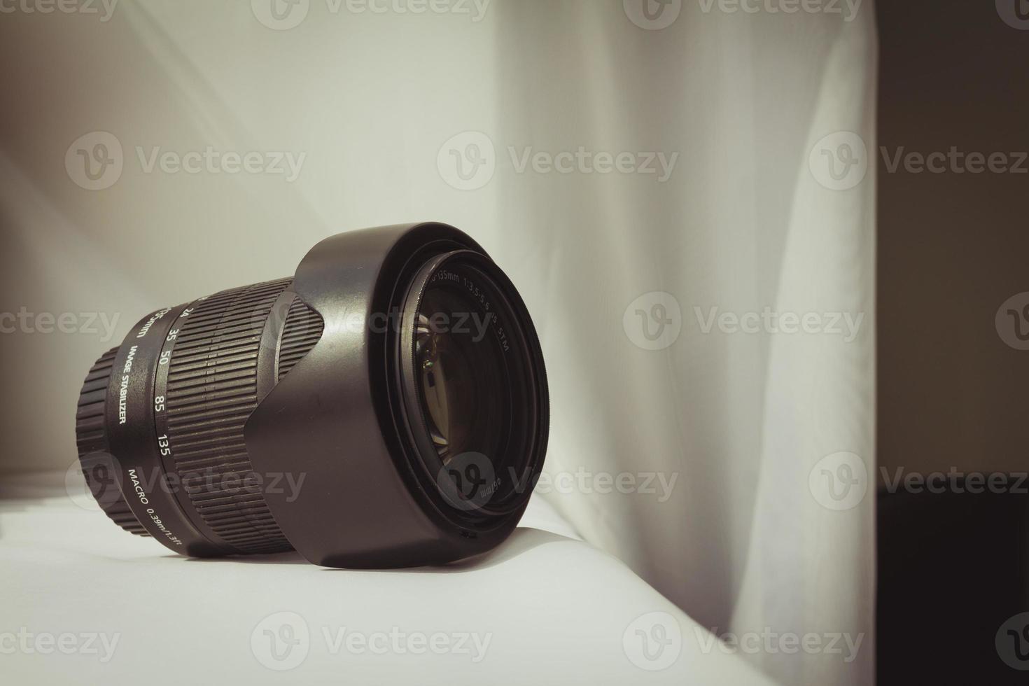 Black camera zoom lens on white cloth photo