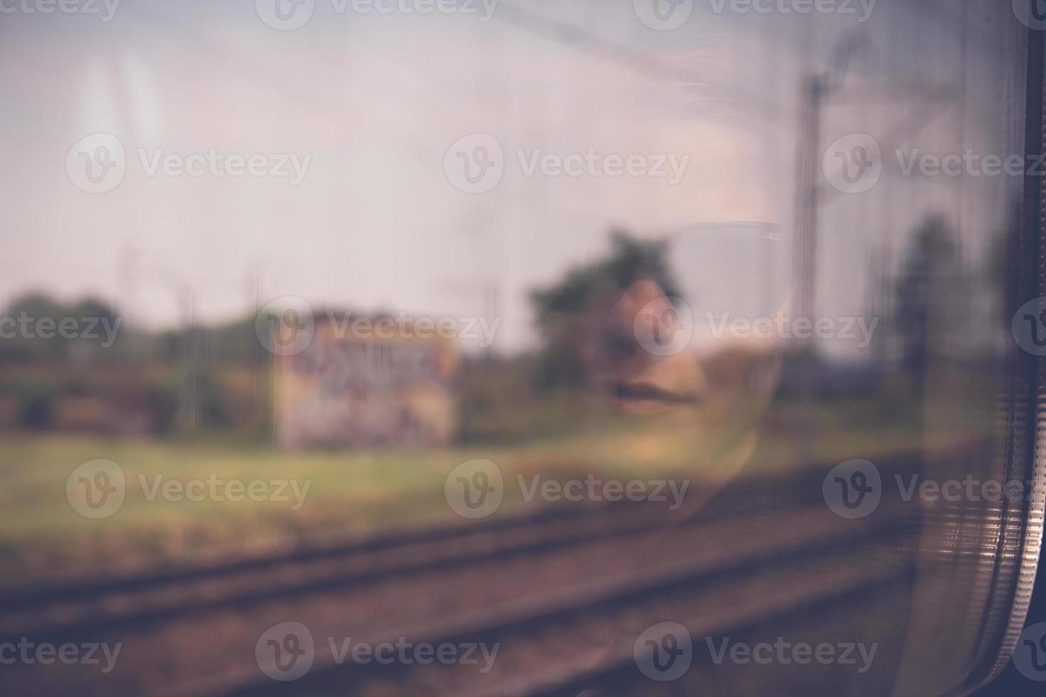 Mysterious woman face with black sunglasses reflected in the window of a traveling train photo