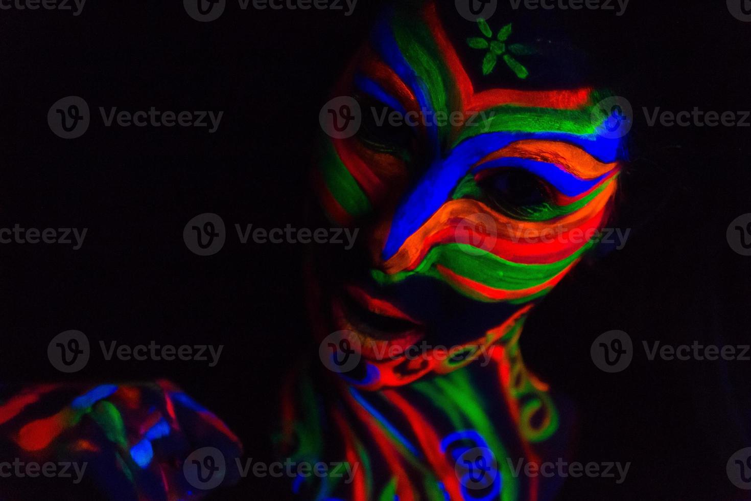 Mujer con arte de maquillaje de polvo fluorescente ultravioleta brillante foto