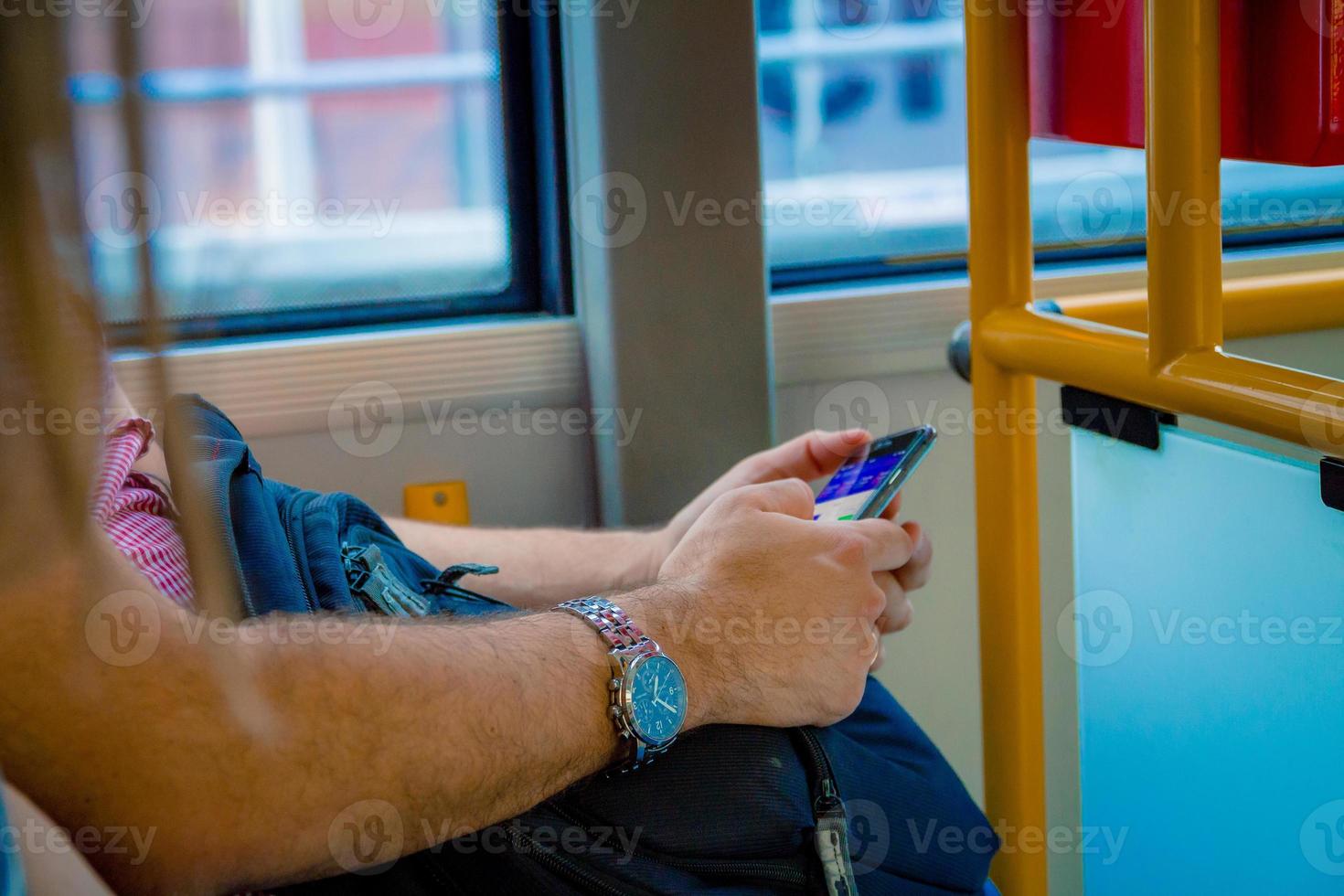 De cerca a un hombre con un teléfono inteligente mientras viaja en autobús en Varsovia, Polonia foto