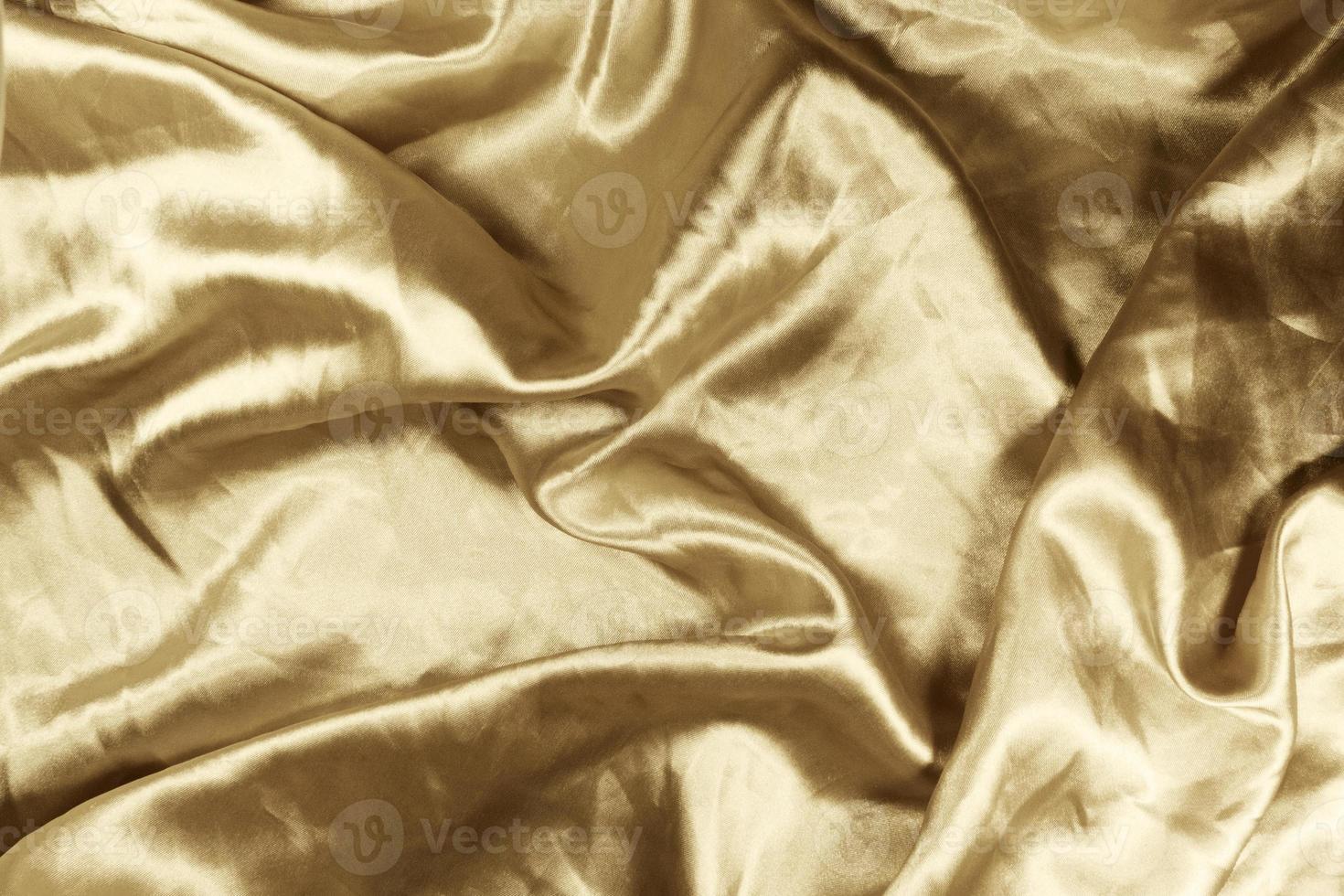 Gold satin background with an abstract design that provides the appearance of glittering waves. photo