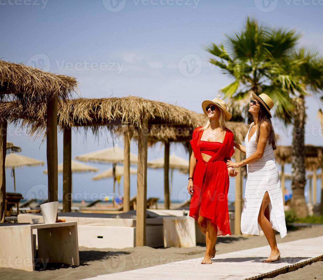 Two young women walking on a beach at summer photo