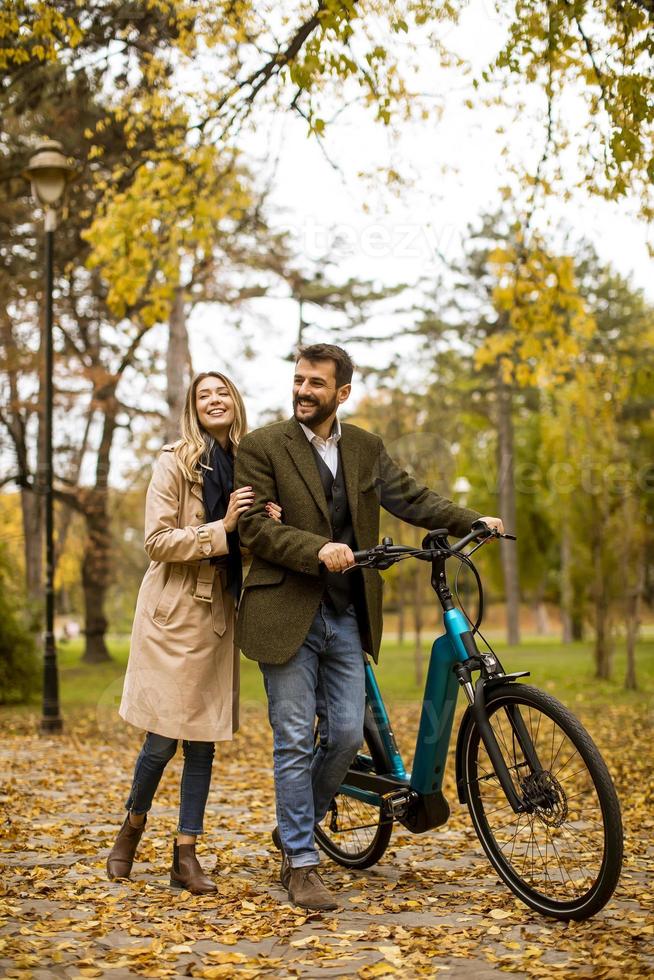 pareja joven, en, el, otoño, parque, con, bicicleta eléctrica foto