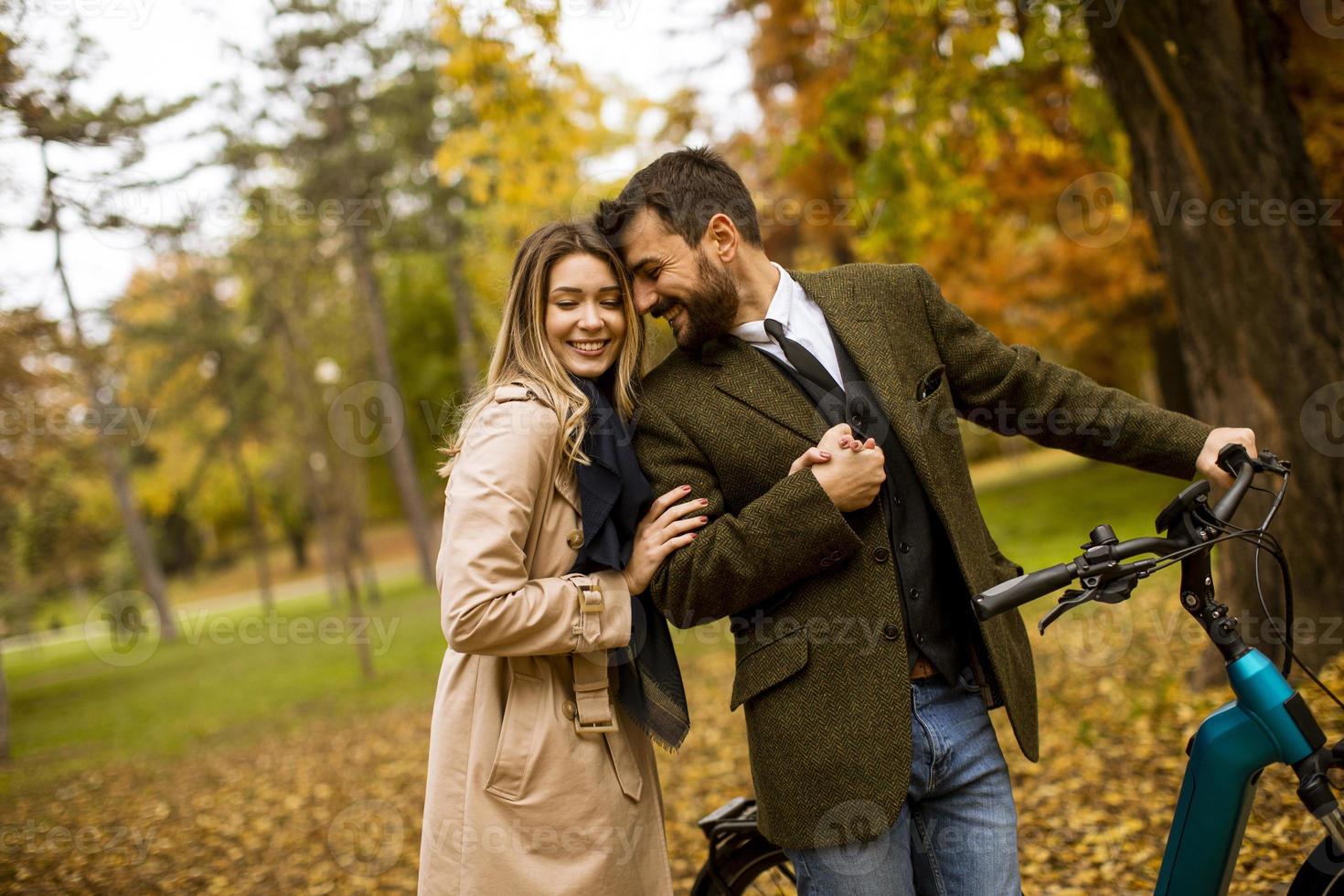 Young couple in the autumn park with electrical bicycle photo