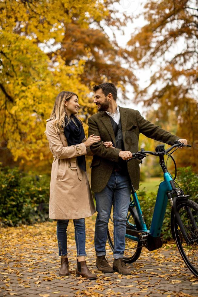 Young couple in the autumn park with electrical bicycle photo