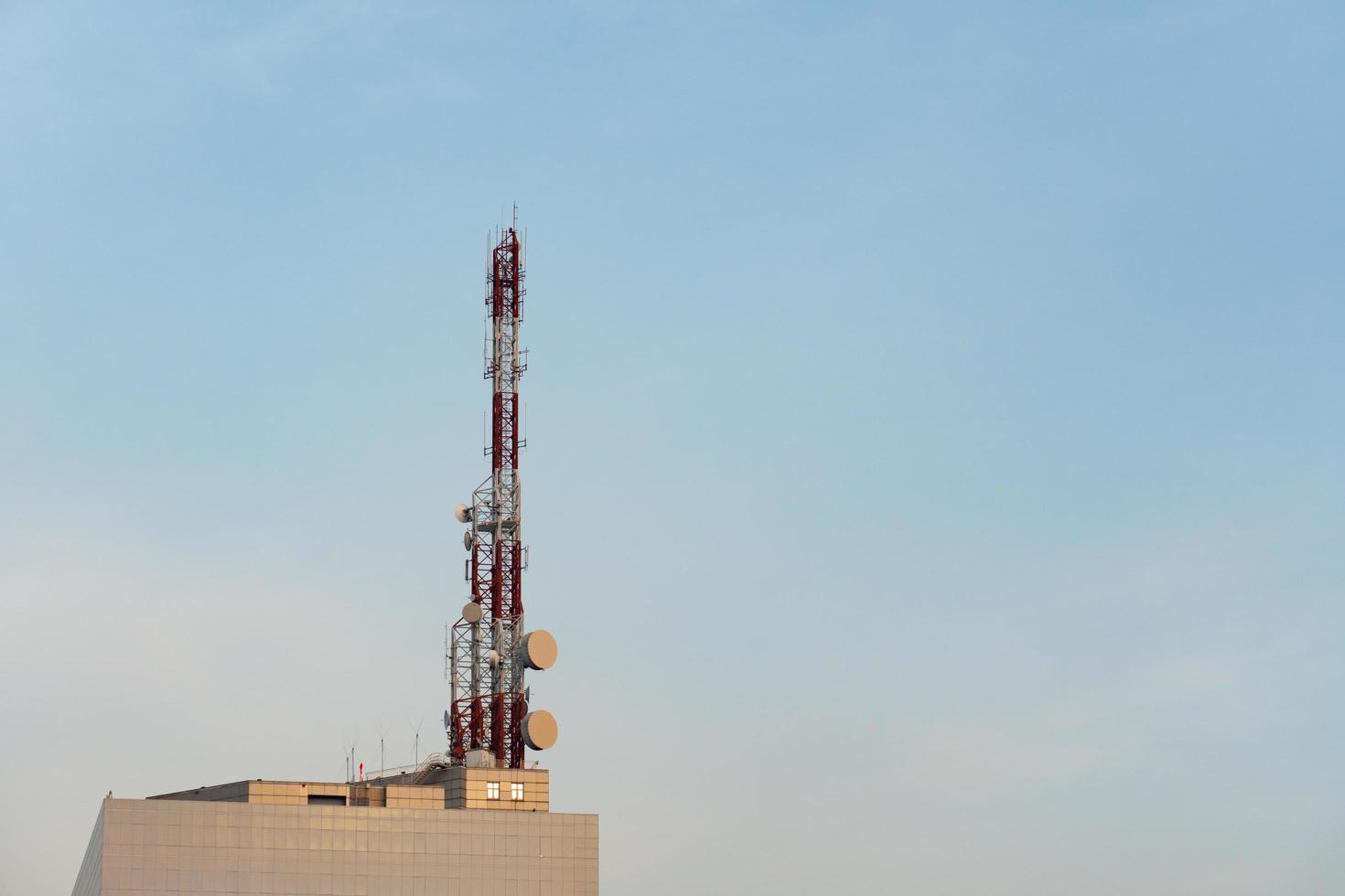 Gran torre de transmisión de Internet y telefonía móvil en la parte superior del edificio bajo un cielo azul foto