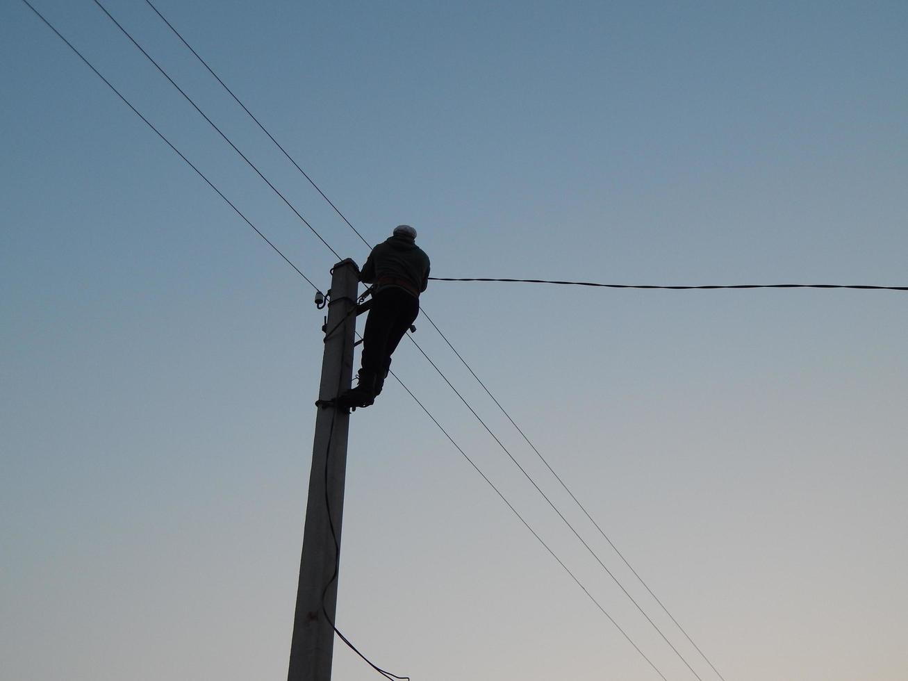 Electrician works in special clothes on the pole photo