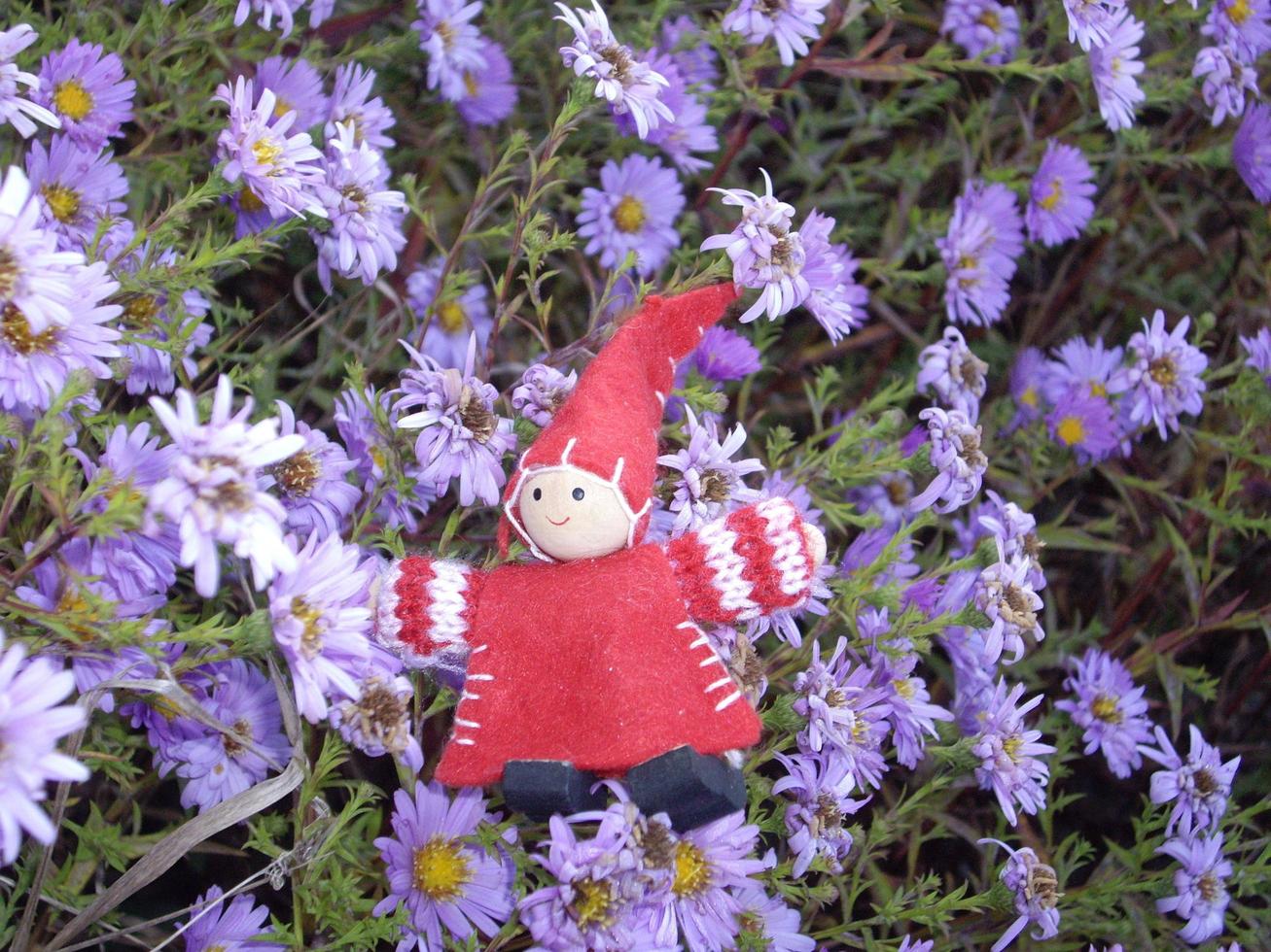 Red little gnome on a background of flowers photo