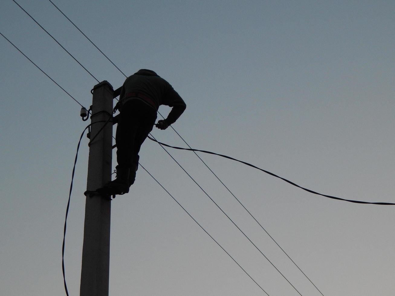 electricista trabaja con ropa especial en el poste foto