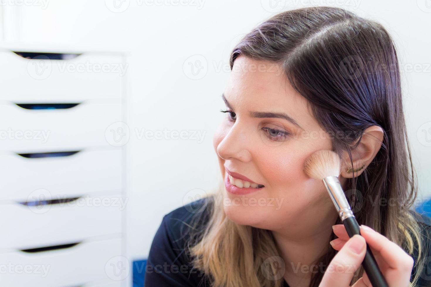 mujer aplicando maquillaje en su dormitorio foto