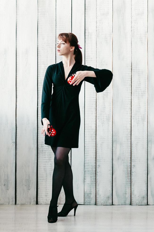 young dancing girl in black dress, with red castanets, light background photo