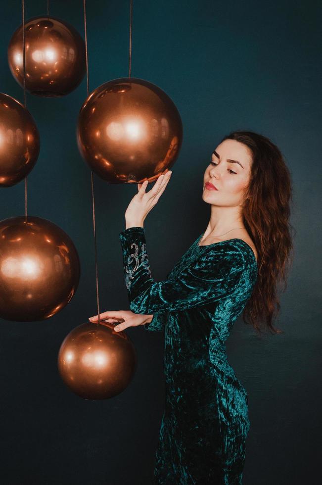 Chica guapa en vestido de lujo, jugando con bolas de oro, año nuevo o concepto de Navidad foto