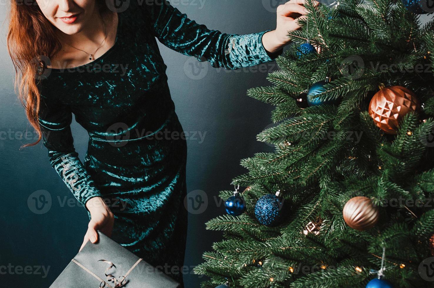 Beautiful woman holding gift box near Christmas tree photo