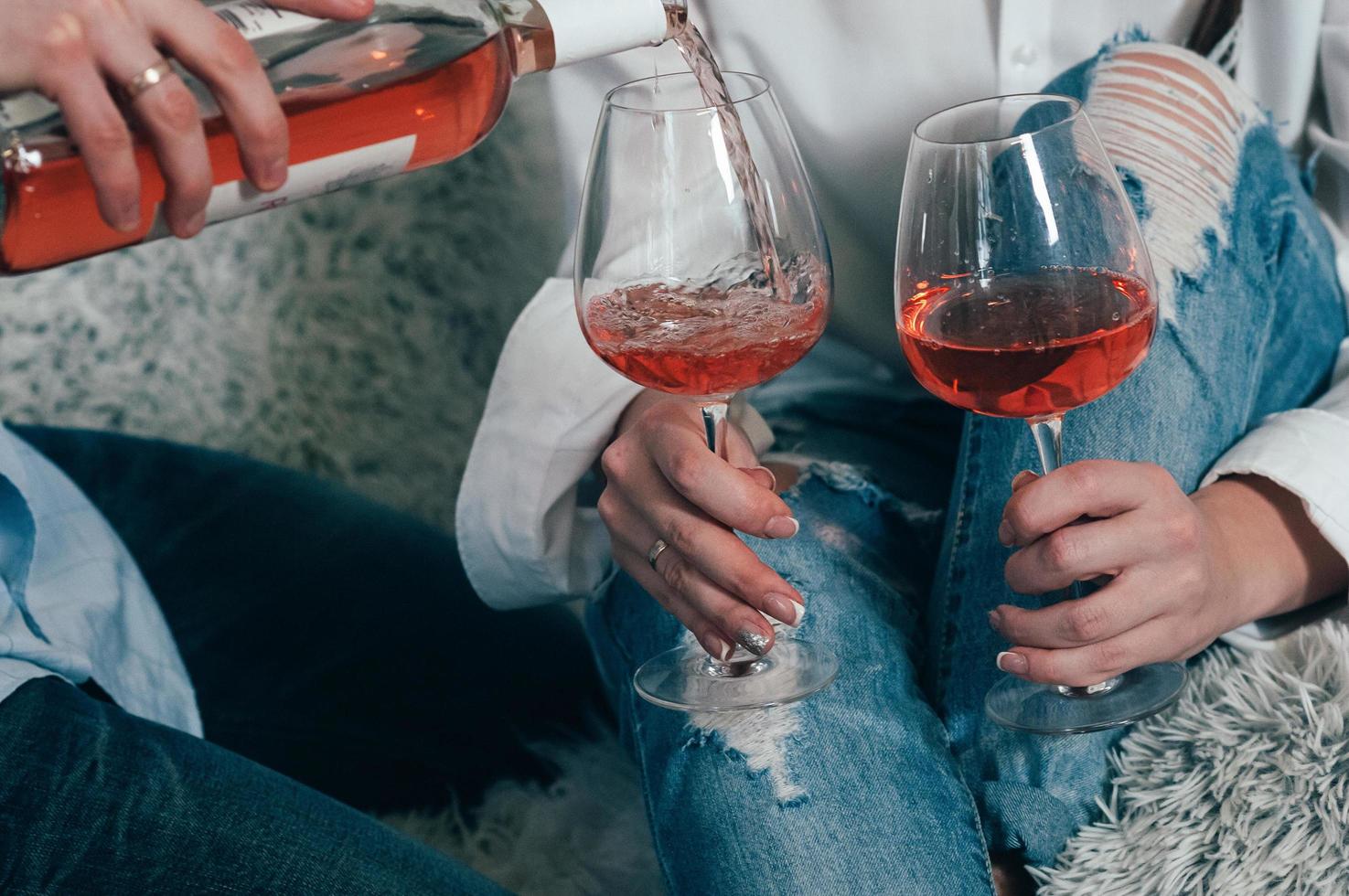 hombre en jeans llena vasos con vino rosado foto