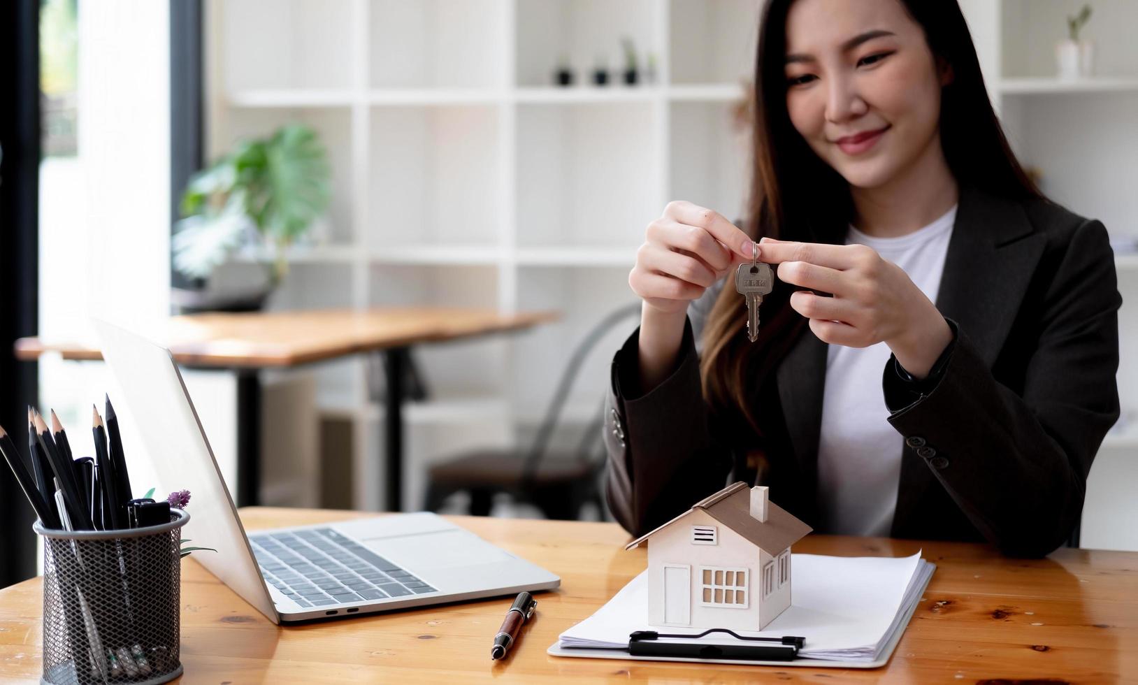 Close up focus on keys, smiling woman realtor selling apartment, offering to client, showing at camera, holding documents, contract, making purchasing deal, real estate agent, mortgage or rent photo