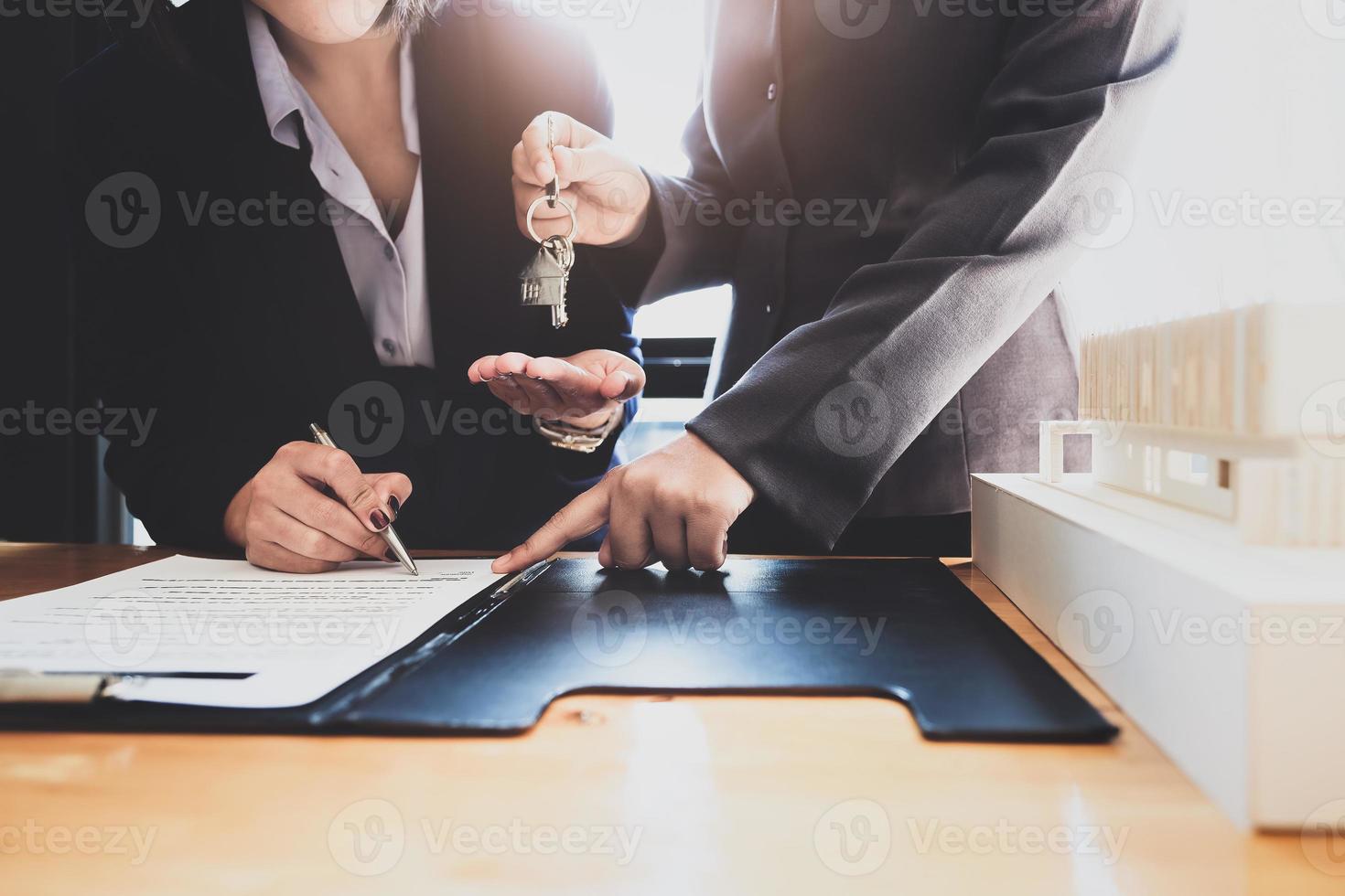 Los agentes inmobiliarios acuerdan comprar una vivienda y entregar las llaves a los clientes en las oficinas de su agencia. acuerdo de concepto. foto