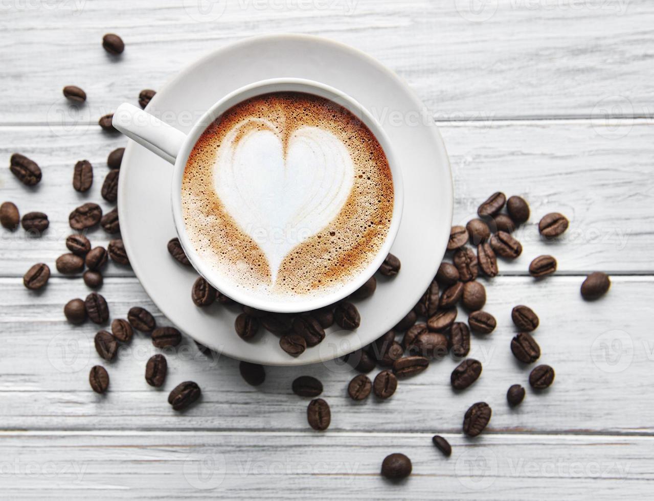 una taza de café con patrón de corazón en una mesa foto