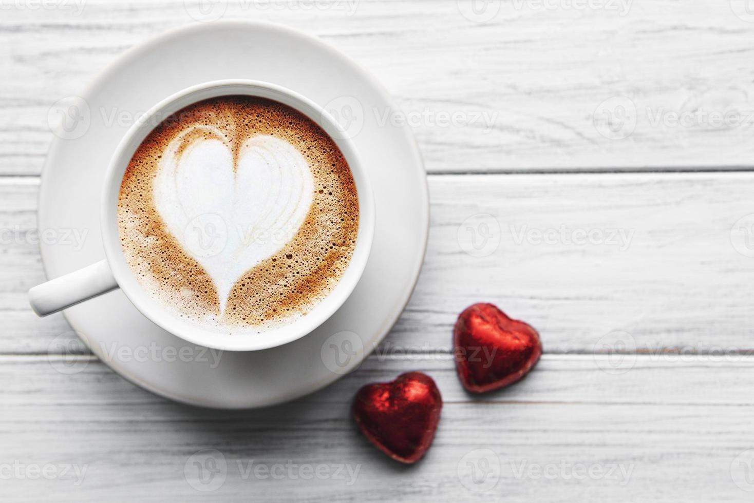 una taza de café con patrón de corazón en una mesa foto