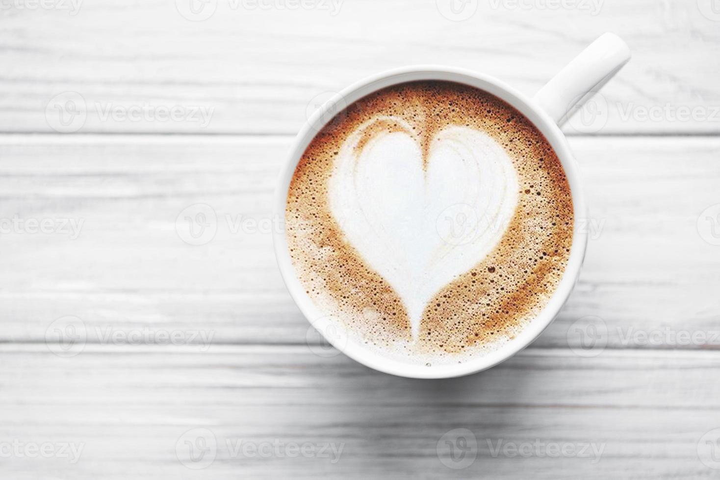 una taza de café con patrón de corazón en una mesa foto