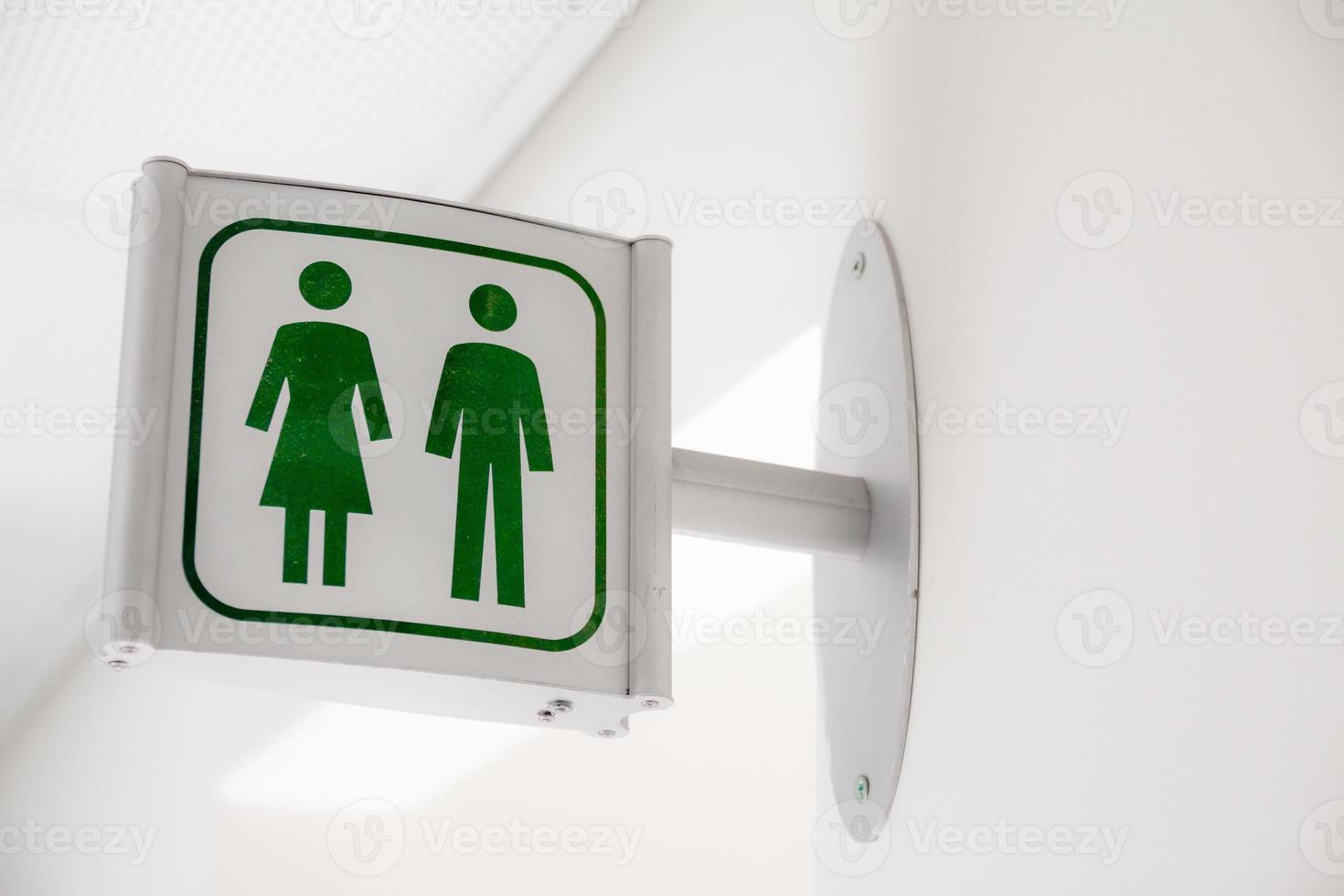 Signo de baño público moderno blanco y verde en la pared blanca foto