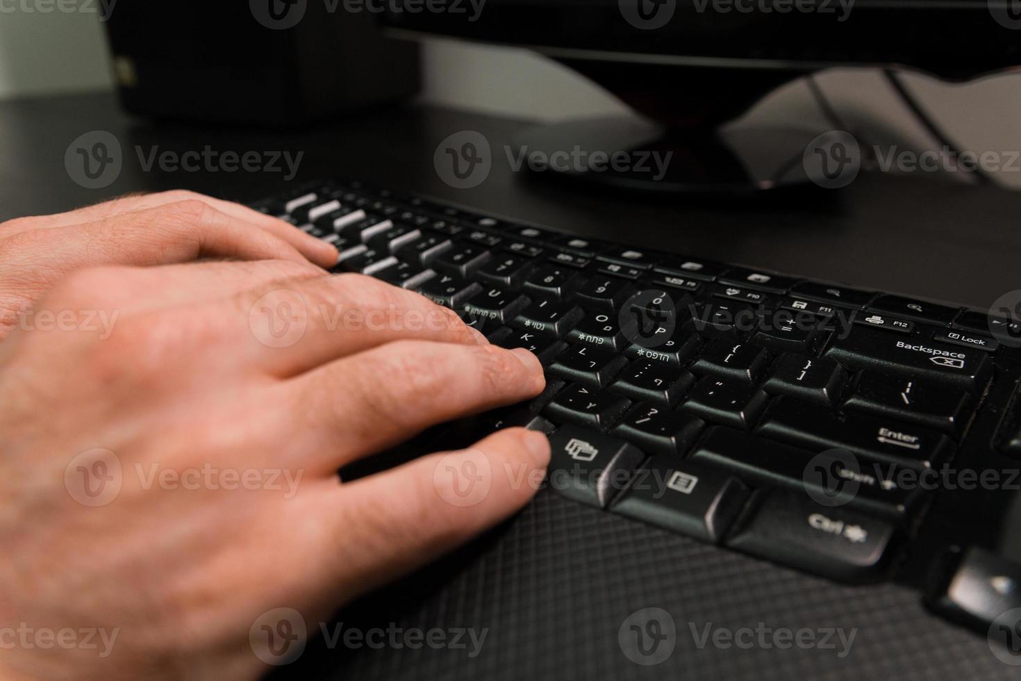 Man typing on a keyboard with letters in Hebrew and English photo