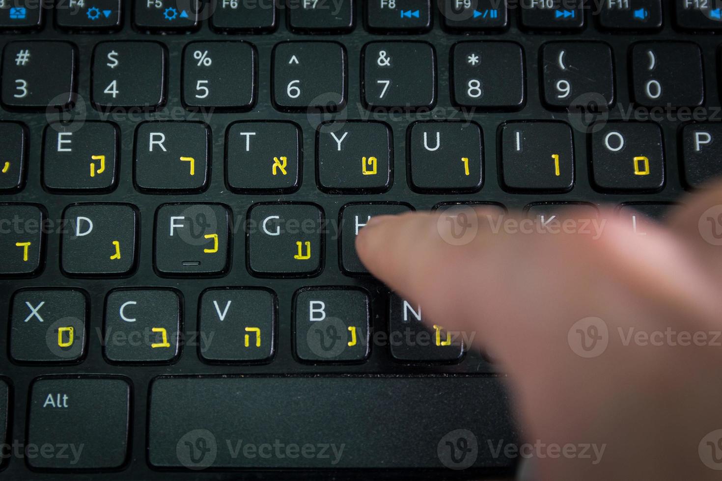 Man typing on a keyboard with letters in Hebrew and English photo