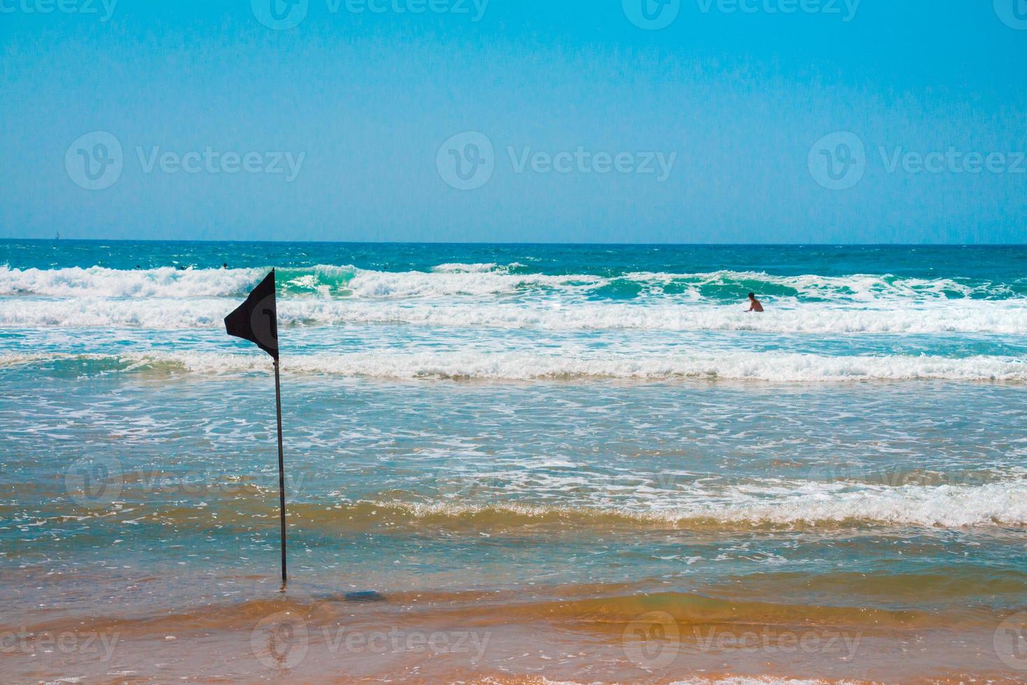 Bandera de advertencia negra que marca el límite de la zona segura para nadar en una hermosa playa con un cielo azul y un mar turquesa en Israel foto