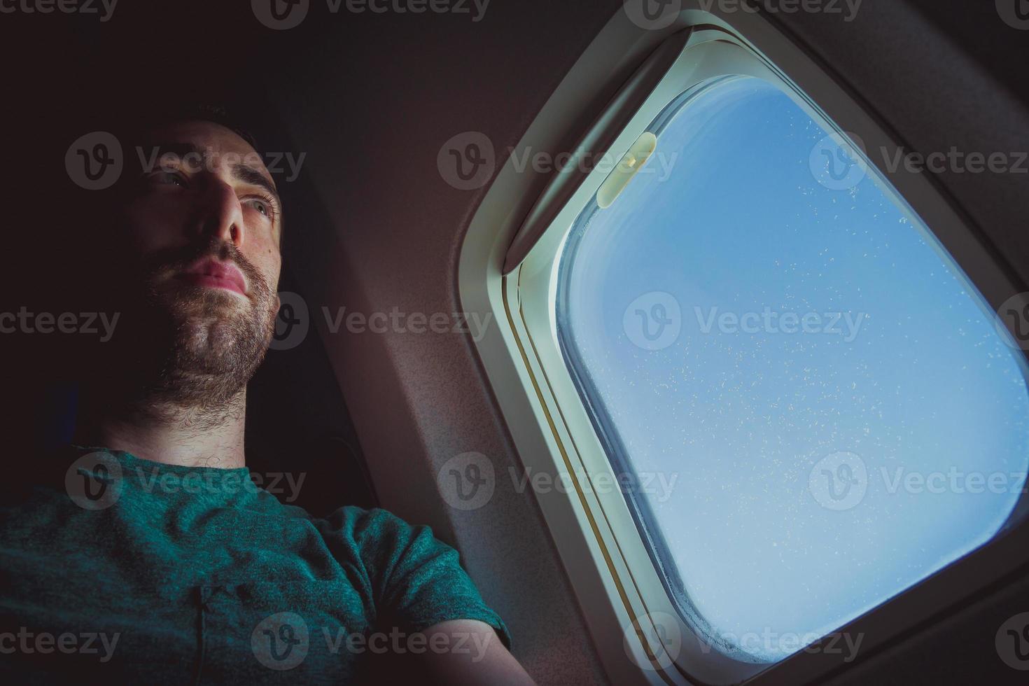 Pensive man seat by the window of an airplane photo