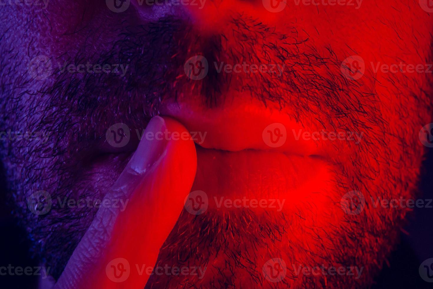 Macro close up on man with thoughtful facial expression with his finger to his lips photo