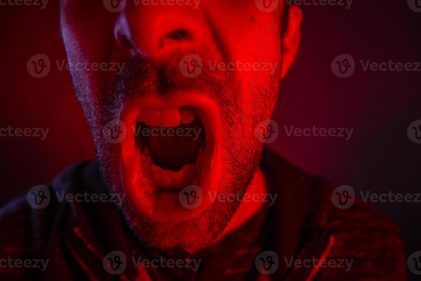 Man with angry facial expression screaming out loud photo