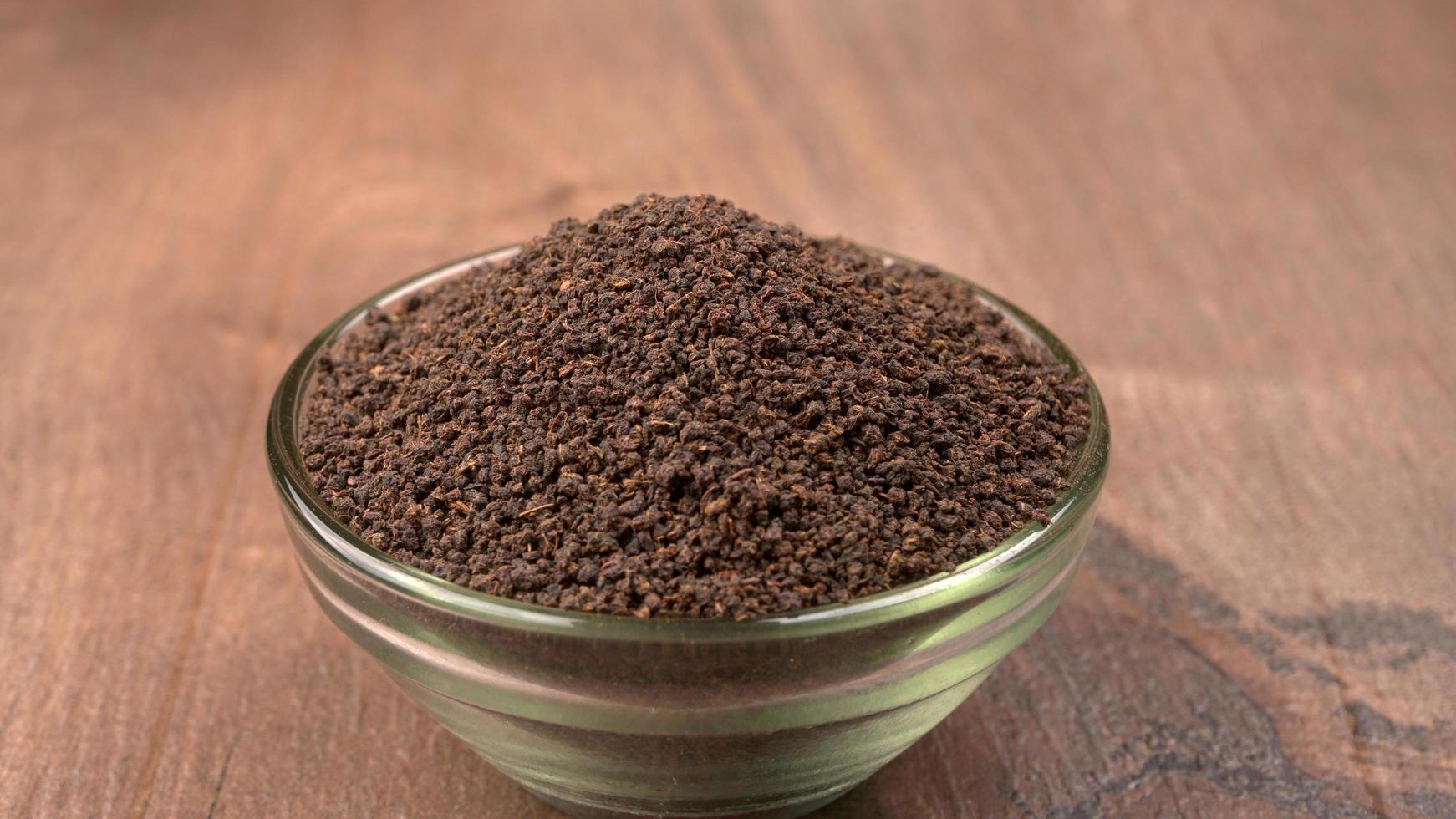 Black Tea Powder or dry dust tea powder, chai patti isolated in wooden bowl. photo