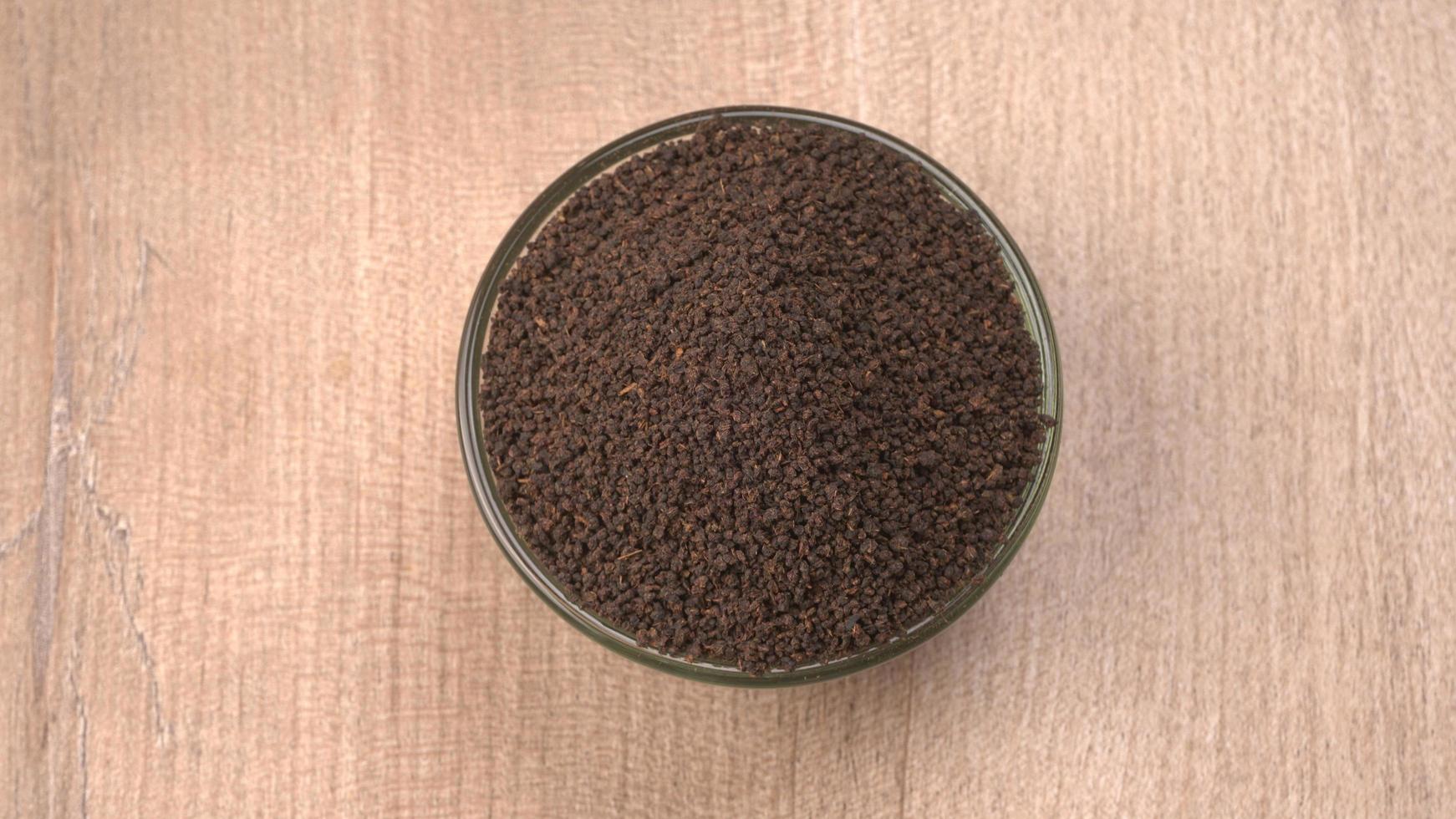 Black Tea Powder or dry dust tea powder, chai patti isolated in wooden bowl. photo