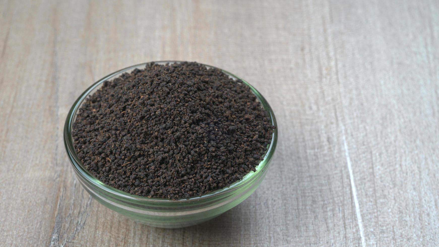 Black Tea Powder or dry dust tea powder, chai patti isolated in wooden bowl. photo