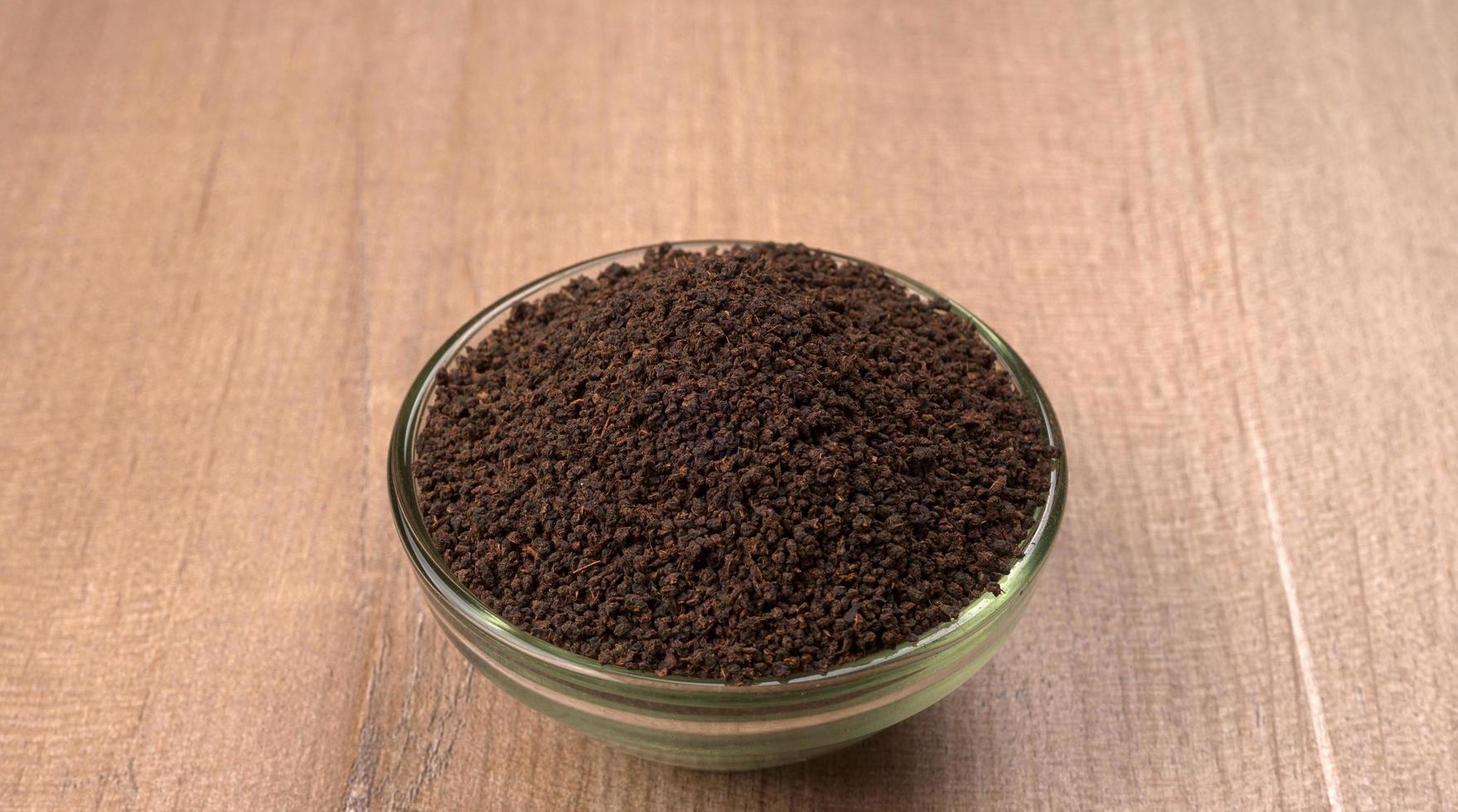 polvo de té negro o polvo de té en polvo seco, chai patti aislado en un tazón de madera. foto