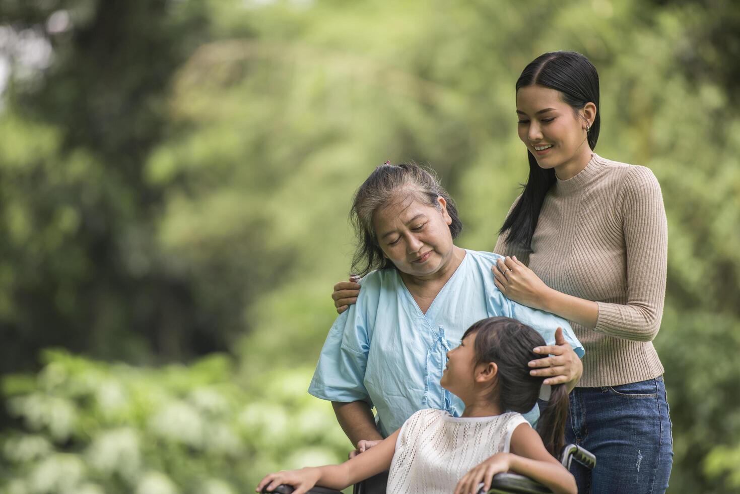 Happy grandmother in wheelchair with her daughter and grandchild in a park, Happy life Happy time. photo