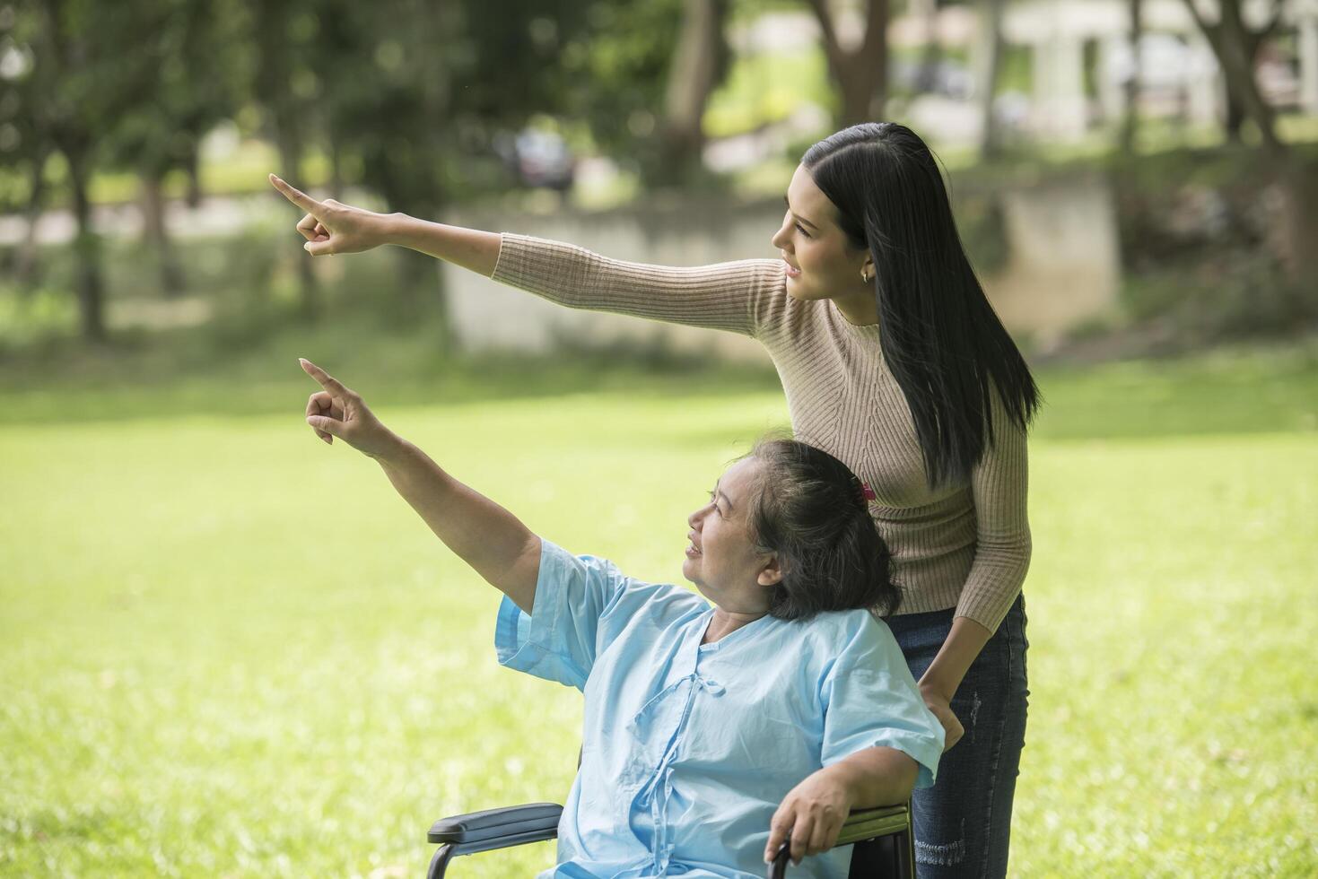 nieta hablando con su abuela sentada en silla de ruedas, concepto alegre, familia feliz foto