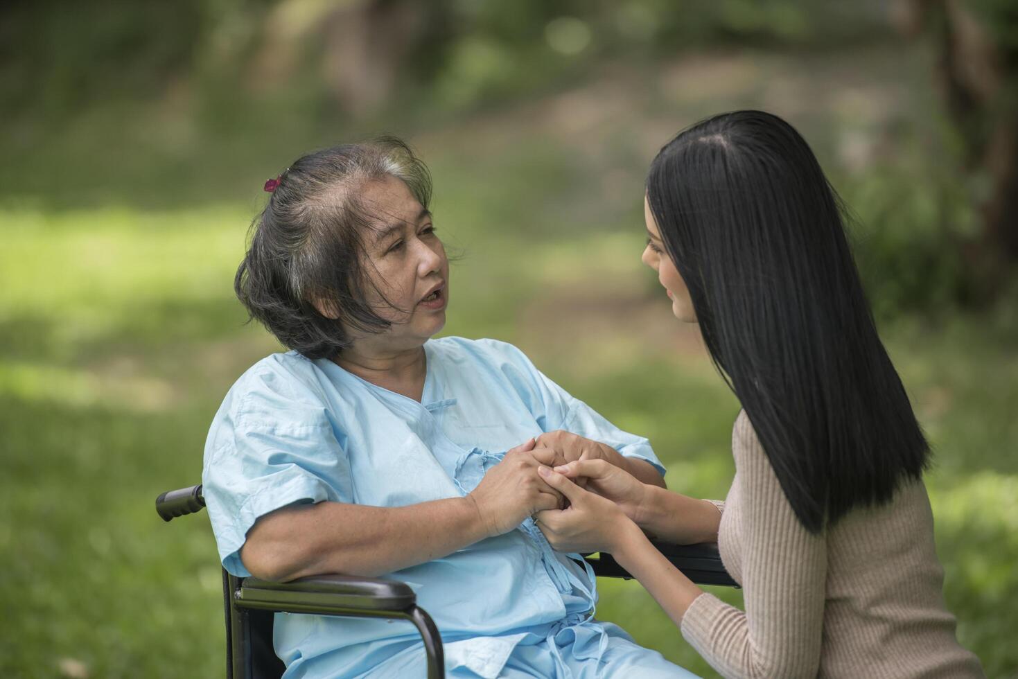 nieta hablando con su abuela sentada en silla de ruedas, concepto alegre, familia feliz foto