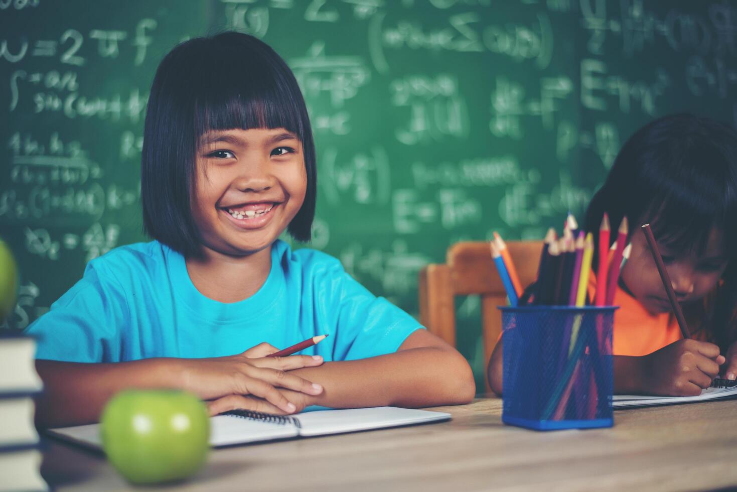 Dos niñas con dibujo a lápiz en la lección en el aula foto