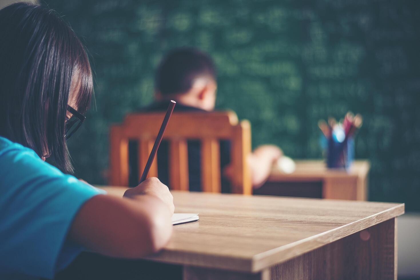 girl with crayon drawing at lesson in the classroom photo