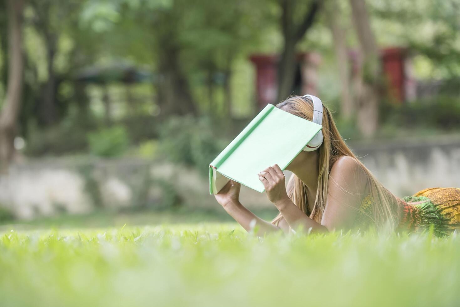 Asian woman listening favorite music on headphones and reading a book. Happy time and relax. photo