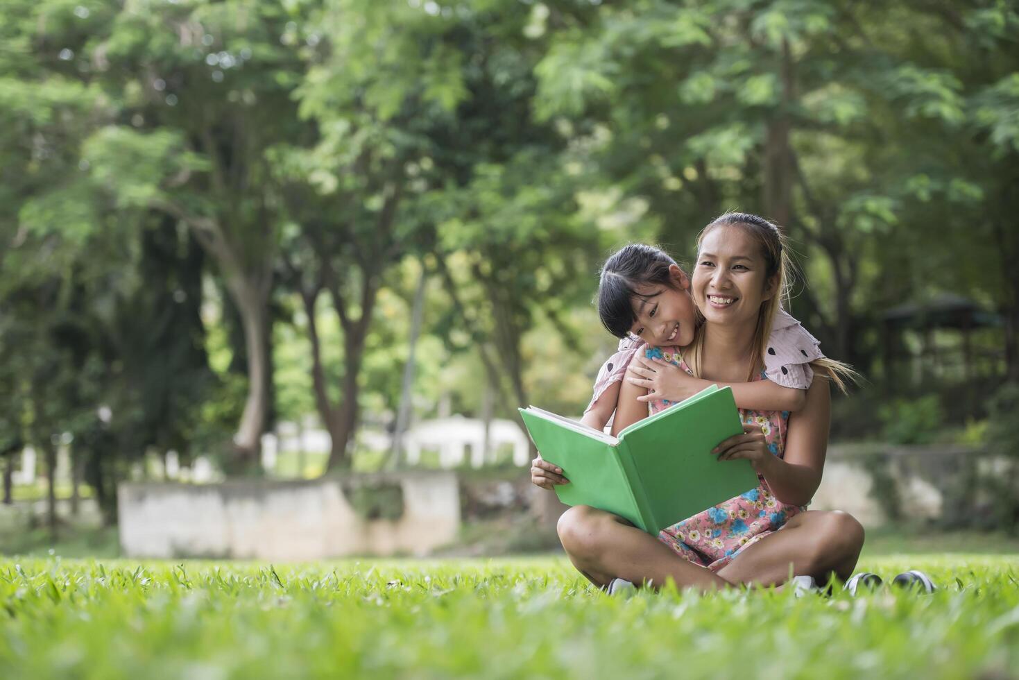 madre e hija leyendo un cuento de hadas a su hija en el parque foto