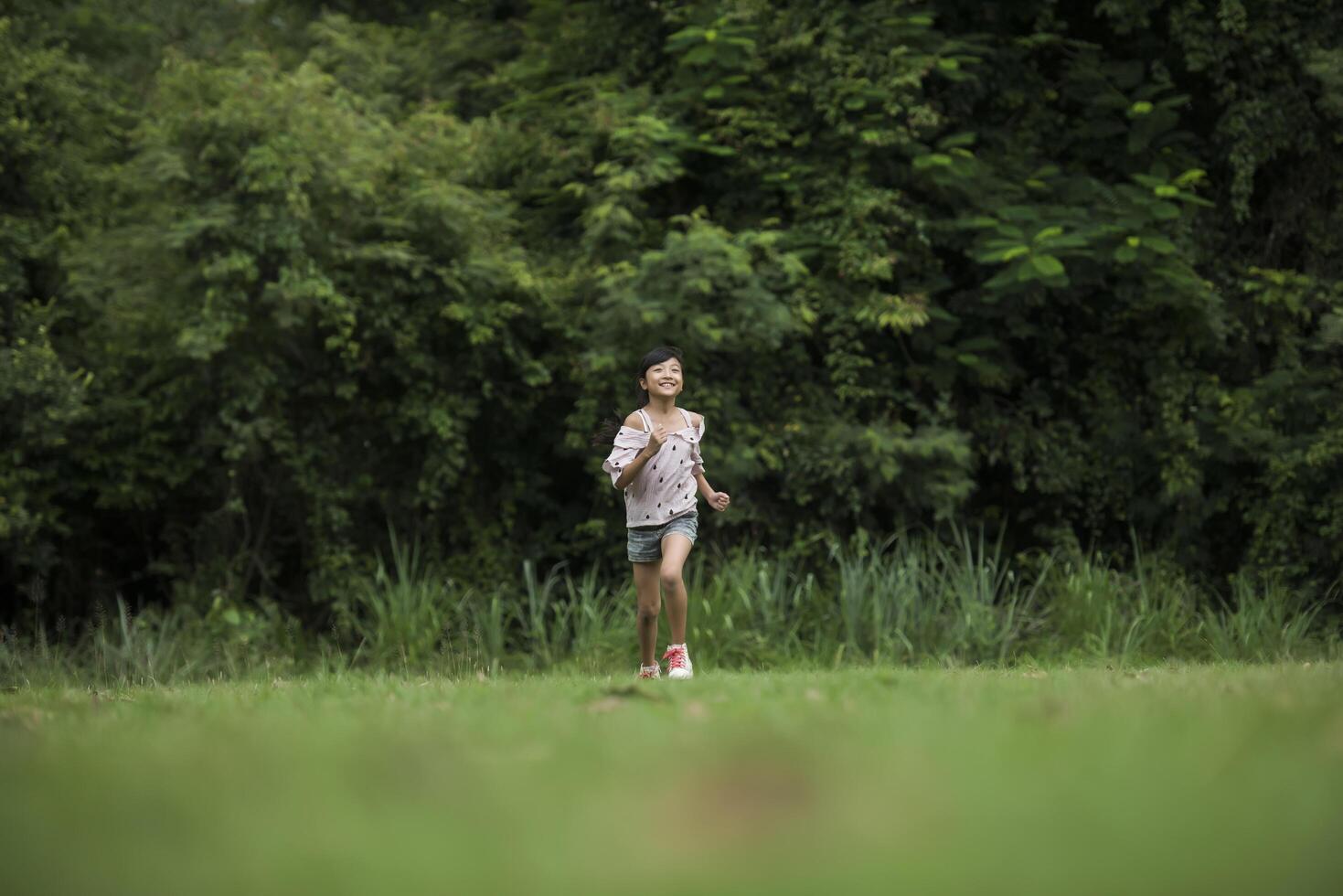 Happy cute little girl running on the grass in the park photo