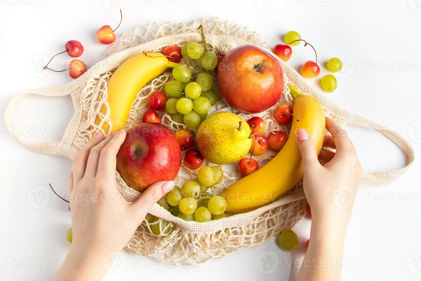 mujer pone fruta madura en una bolsa de malla ecológica para ir de compras. Las manos femeninas sostienen una bolsa de hilo de algodón con productos agrícolas orgánicos. estilo de vida sostenible. foto