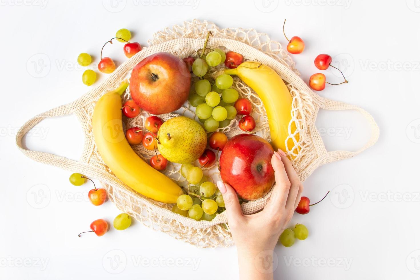 mujer pone fruta madura en una bolsa de malla ecológica para ir de compras. Las manos femeninas sostienen una bolsa de hilo de algodón con productos agrícolas orgánicos. estilo de vida sostenible. foto