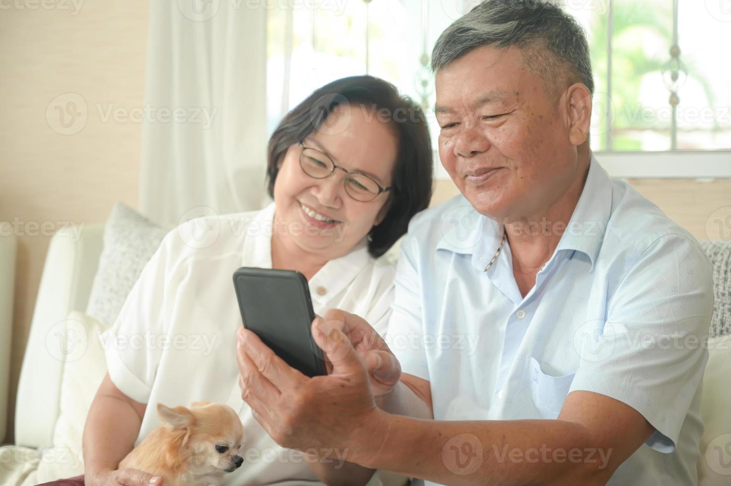 hombres y mujeres mayores están usando su teléfono inteligente en el sofá. foto
