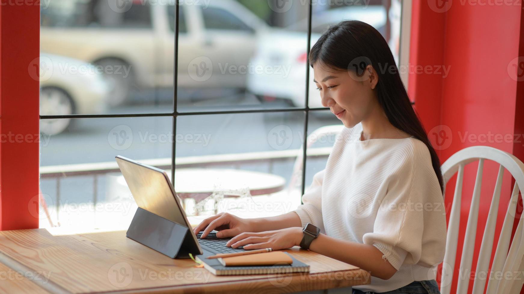 La sirvienta independiente está usando una computadora portátil para hacer un nuevo proyecto para presentar a los clientes en una cafetería. foto