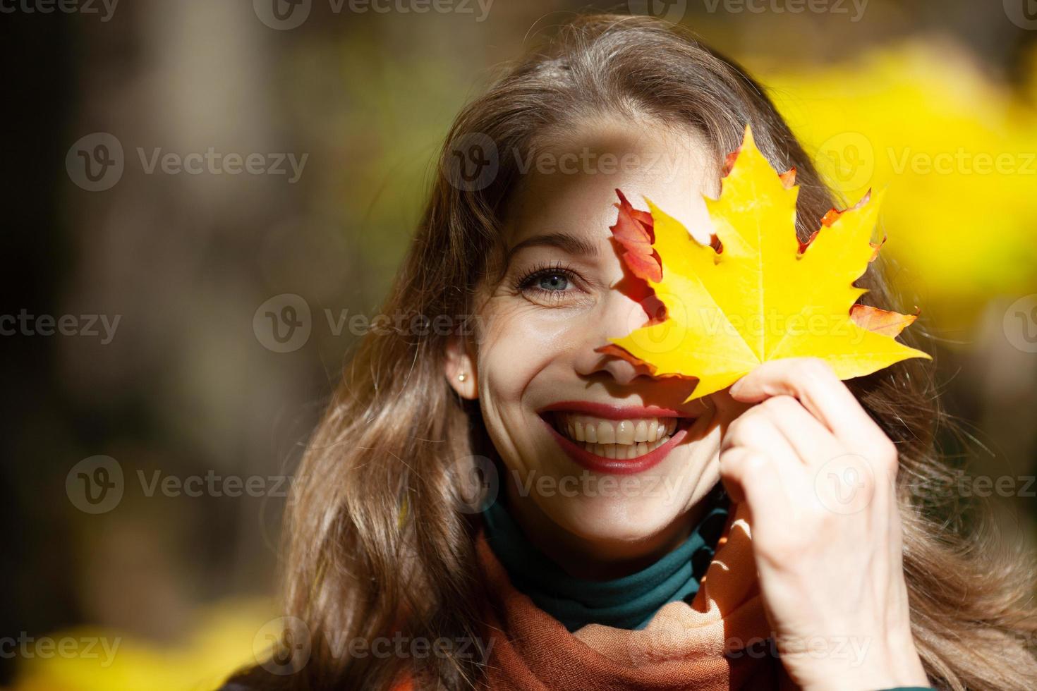 Young woman holding a maple leaf near her face photo