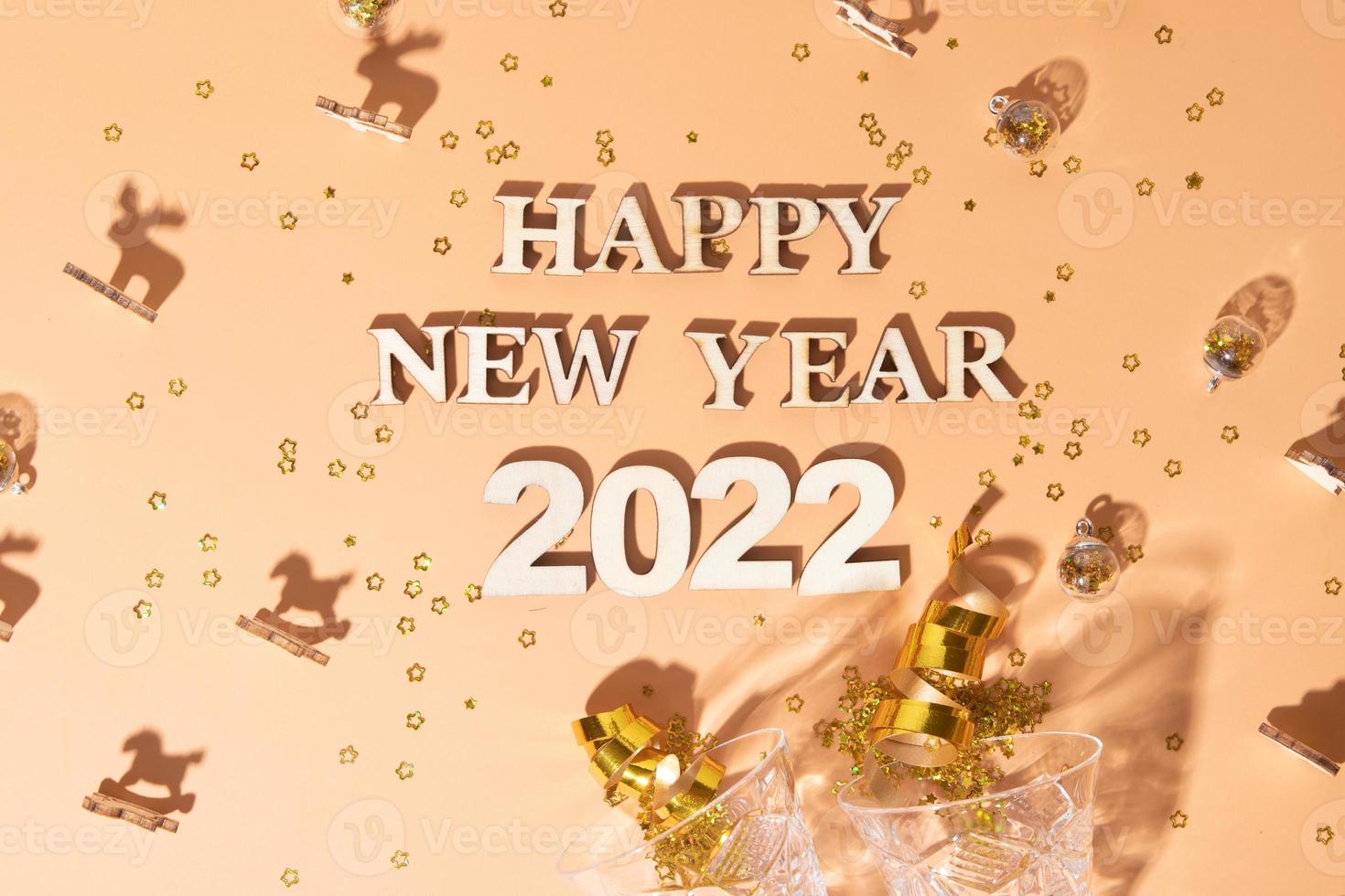 Festive new year flat lay with numbers 2022 and hard shadows with glasses and shiny decor photo