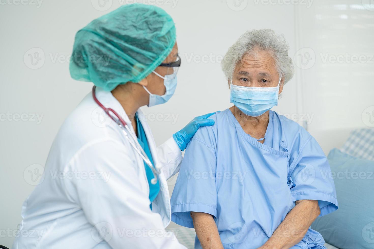 Doctor help Asian senior or elderly old lady woman patient wearing a face mask in hospital for protect safety infection and kill Covid-19 Coronavirus. photo