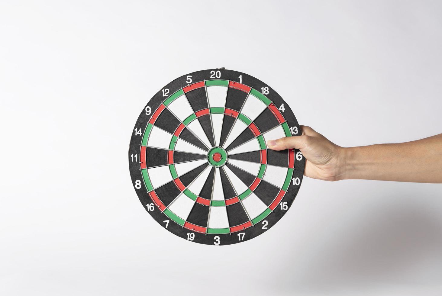 Hand holding target dart board on gray background. photo